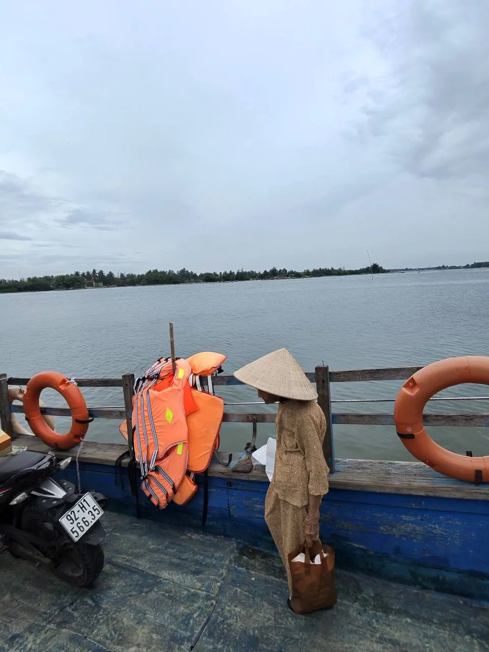 Phà — người đội nón lá, phao cam, xe máy trên boong